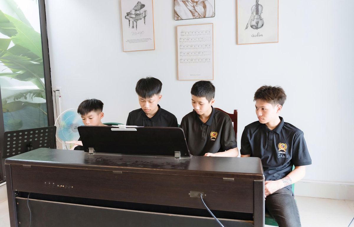Thầy giáo kiên nhẫn hướng dẫn học viên cách đặt tay đúng tư thế trên phím đàn